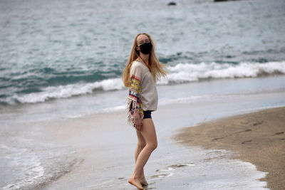 Side view of woman wearing mask walking at beach