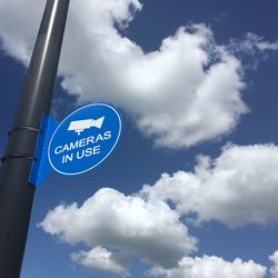 Low angle view of road sign against blue sky