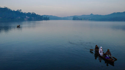 People in boat on lake against sky