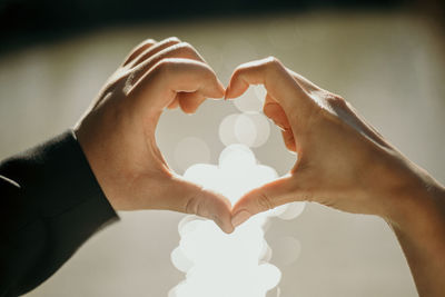 Cropped image of couple making heart shape