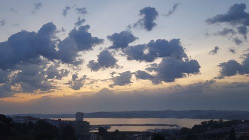 Silhouette city by sea against sky during sunset