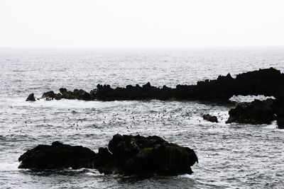 Scenic view of rocks in sea against clear sky