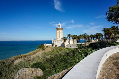 Lighthouse by sea against sky