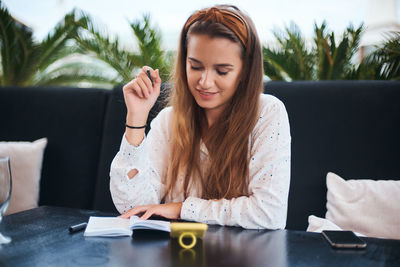 Woman looking at camera while sitting on table