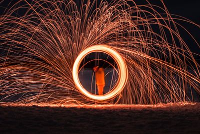 Young man spinning illuminated wire wool at night