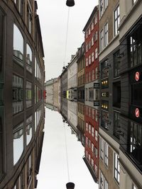 Directly below shot of buildings by canal against sky