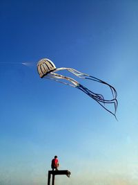 Low angle view of man paragliding against blue sky