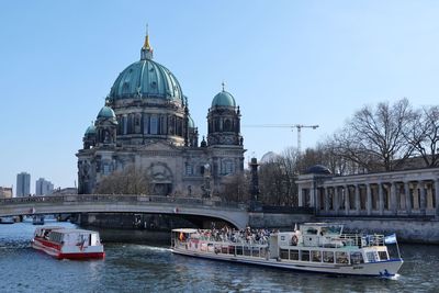 Ferry boats sailing in spree river against berlin cathedral