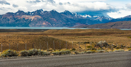 Scenic view of road by mountains against sky