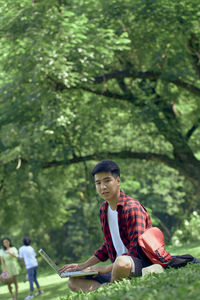 Young man sitting on tree