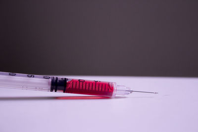 Close-up of blood sample in syringe on table against black background