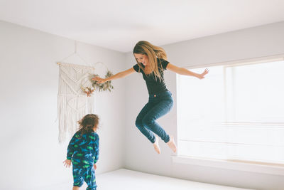Mother and son jumping on bed at home