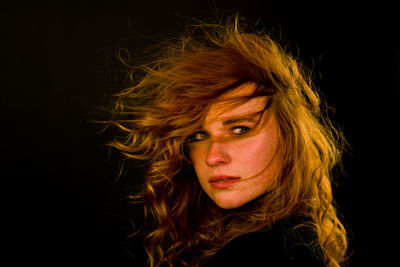 Close-up portrait of a beautiful young woman over black background