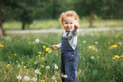 Portrait of cute girl holding flower on field