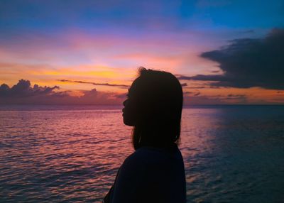 Silhouette man looking at sea against sky during sunset