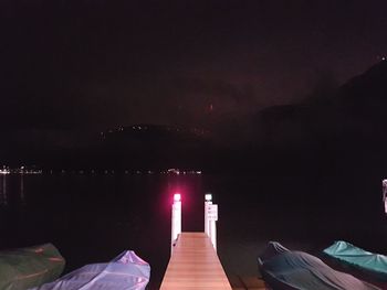 Man relaxing on illuminated bridge against sky at night