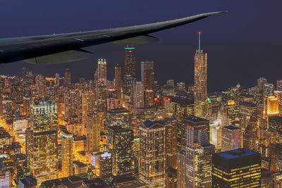 Illuminated modern buildings in city against sky at night