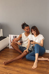 Happy stylish, modern, multiracial couple, a guy and a girl , sit at home on the floor 