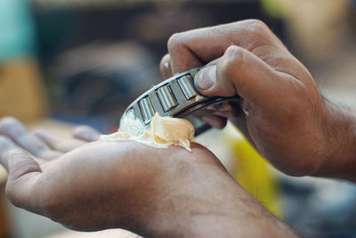 Cropped hands of mechanic holding tool and grease