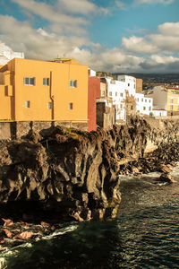 Buildings by sea against sky in city