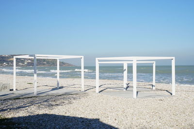 Lifeguard hut on beach against clear blue sky