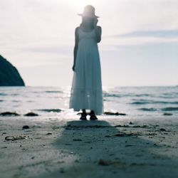 Rear view of man standing on beach against sky