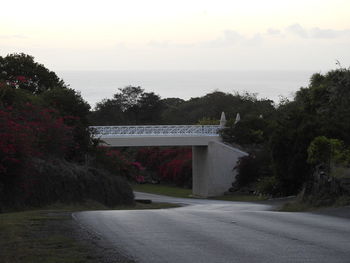 View of road by building against cloudy sky