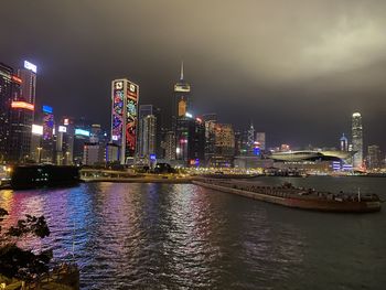River by illuminated buildings against sky at night