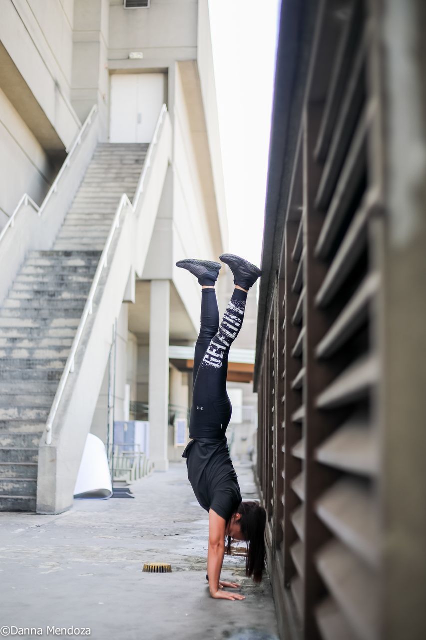 WOMAN ON STAIRCASE AGAINST BUILDING