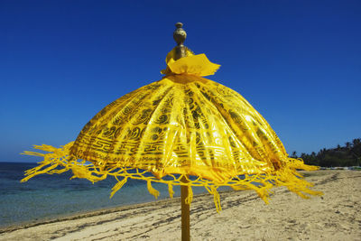 Yellow parasol at beach against clear blue sky