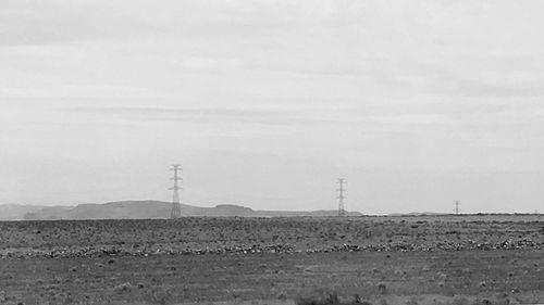 Electricity pylon on field against sky