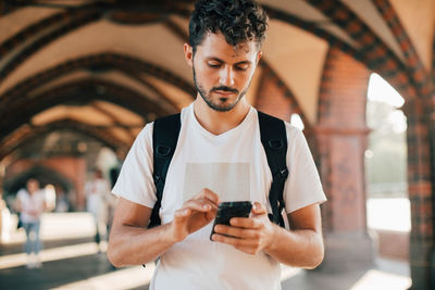 Young man using smart phone while standing on footpath