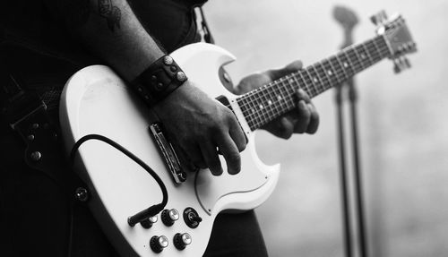 Midsection of man playing guitar