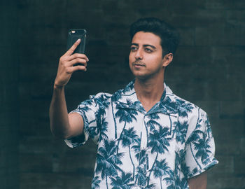 Smiling young man taking selfie through mobile phone