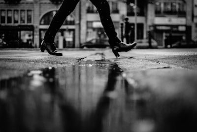 Surface level of woman in high heels walking by puddle on street