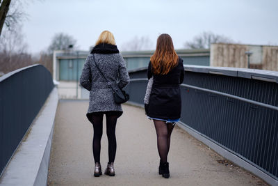 Rear view of women walking on footbridge