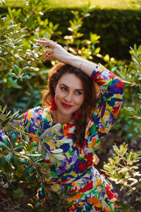 Portrait of smiling young woman standing against plants