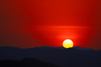 Scenic view of silhouette mountain against orange sky