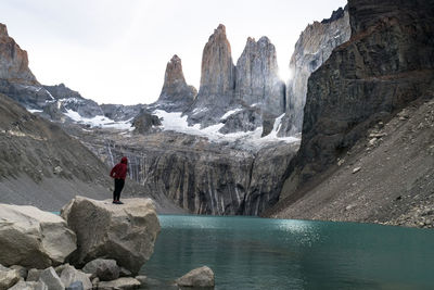 Man standing on rocks by mountain against sky