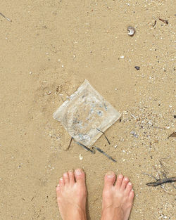 Low section of person standing above plastic found on the beach