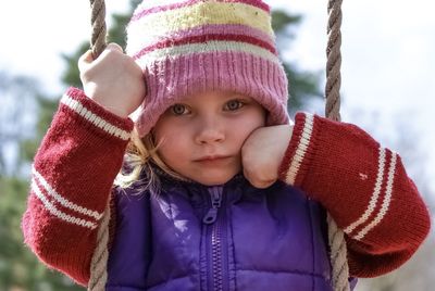 Portrait of cute girl sitting on swing outdoors