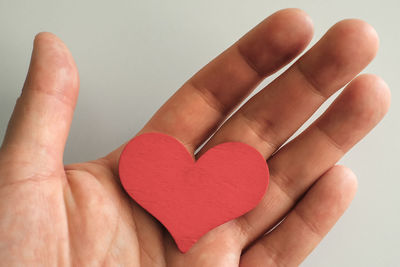 Close-up of hand holding heart shape over white background