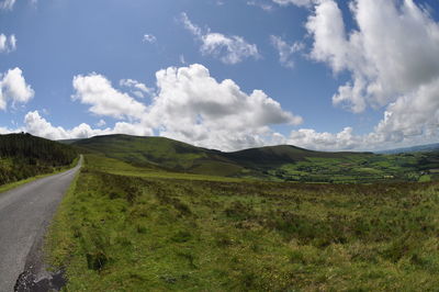 Panoramic view of road amidst field against sky