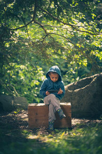 Full length of boy sitting in forest