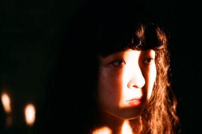 Portrait of young woman against black background