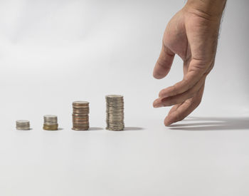 Close-up of hand holding coins over white background