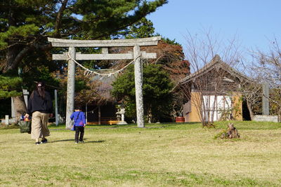 Rear view of people walking on field against trees