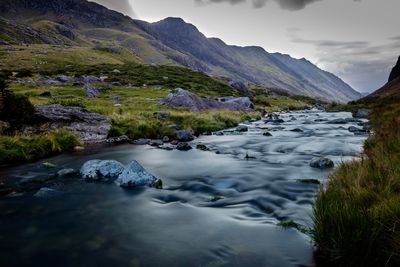 Scenic view of river by mountains against sky