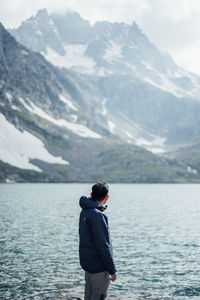 Rear view of man standing in lake against mountains