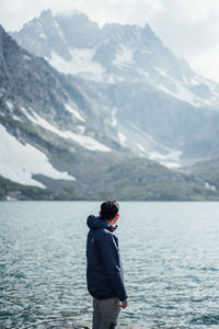 Rear view of man standing in lake against mountains